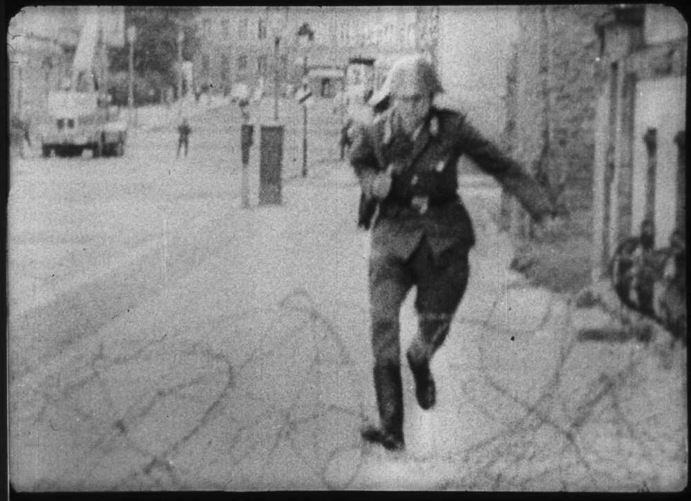 Police officer jumping over barbed wires during the tension period.