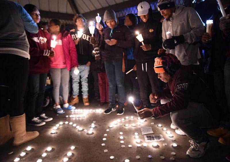 Zack Dobson, bottom right, lights candles to honor his slain brother, Zaevion Dobson, at Sam E. Hill Park in Knoxville on Friday, Dec. 18, 2015